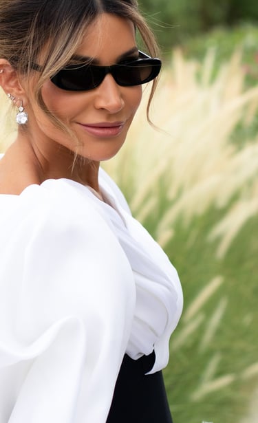 Close-up of woman in black and white gown with puffed sleeves and black sunglasses.