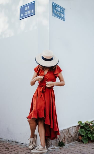 une femme en robe rouge avec chapeau au coin de la rue de l'amour et de la rue du soupir