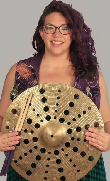 Rachel holding a cymbal with holes through out it, smiling 