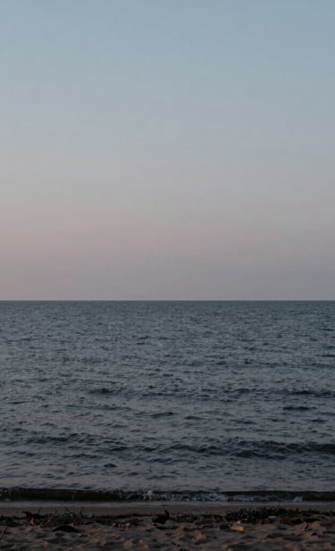 A minimalist landscape photography of the quiet Lake Ontario shoreline at dusk, near black water contrasting with a light grey sky, professional composition, capturing a sense of calm and reassurance.