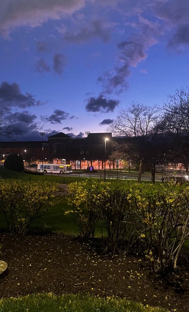 Twilight scene on a university campus with a deep blue sky, streetlights, and brick buildings