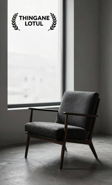 A sophisticated lifestyle photograph of an elegant, minimalist studio space featuring a single mid-century chair in dark charcoal, illuminated by a large window with luminous snow white light.