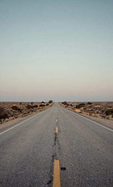 A scenic view of a dusty North American highway stretching toward the horizon at dusk, capturing the spirit of an Americana road trip. Soft, nostalgic, and inviting wide-angle photography. Colors include slate blue-grey, off-white, and copper.