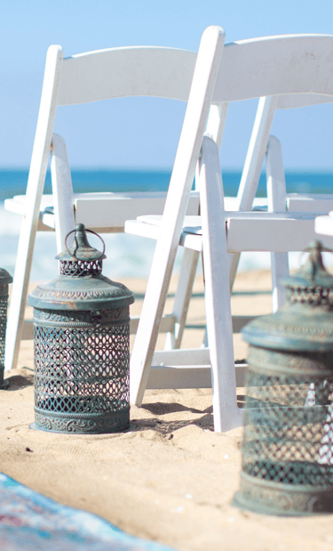 rustic blue metal lantern next to white wedding chair on beach
