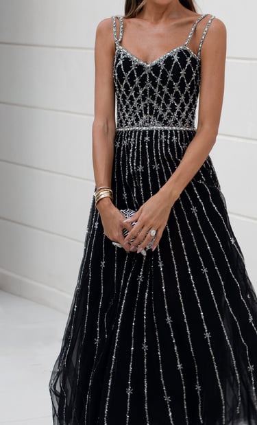 Woman in an elegant black evening gown with silver detailing.