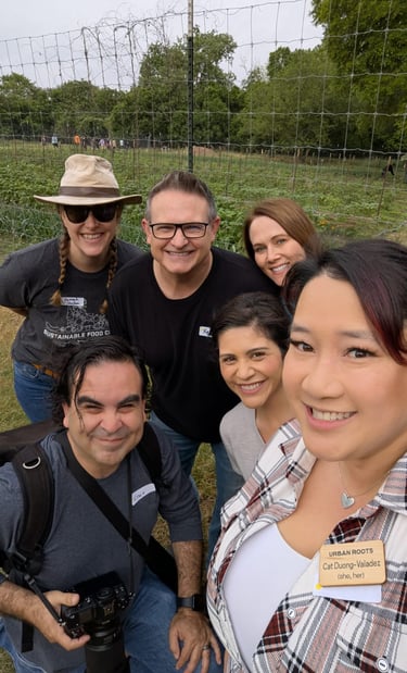 Francisco holds a camera, smiling with fellow volunteers in a joyful outdoor group selfie.