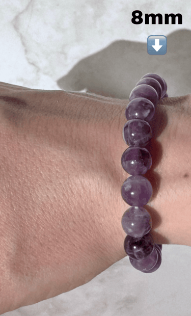 The first half a photo of a wrist with 2 amethyst crystal bracelets on it, this side is the 8mm size