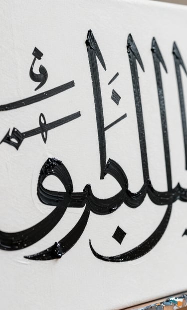 A close-up photograph of a contemporary art canvas in a high-end Middle Eastern studio. Sharp detail of black oil paint texture forming elegant Arabic calligraphy strokes against a stark white background. Natural, bright lighting.