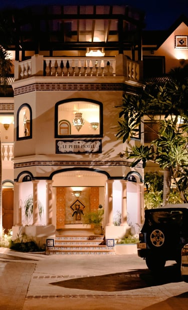 Night view of Le Petit Hotel boutique resort entrance with luxury architecture and parked cars.