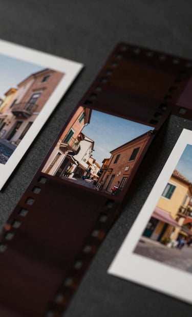 An artistic flat lay of several film strips and printed photographs on a dark #262626 surface. The photos show snippets of Italian life. The lighting is sophisticated, casting gentle shadows across the #C4B29A paper textures.