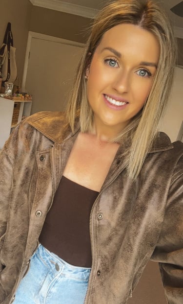 Female smiling wearing a brown jacket and jeans