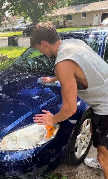 Golden mobile detailing team giving a blue sedan an exterior wash