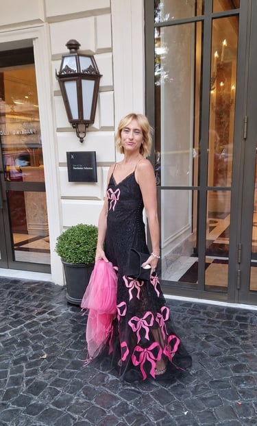 Mary Tornariti outside Hotel Eden Rome in a black gown with pink bows.