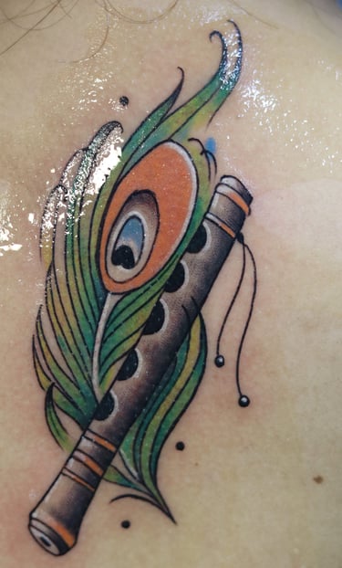 Flute with peacock feather watercolor fill by Dudo's Tattoos Hyderabad