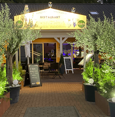a restaurant with a large umbrella and potted plants