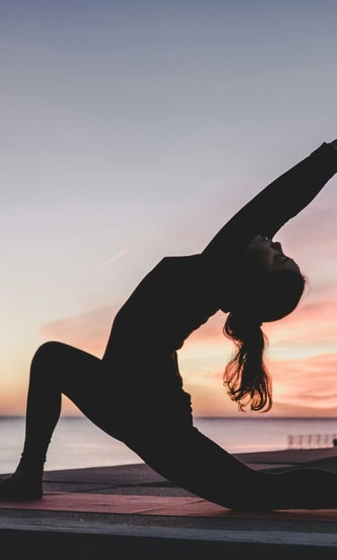 Woman practicing yoga at sunrise by the water, symbolizing peace and natural harmony