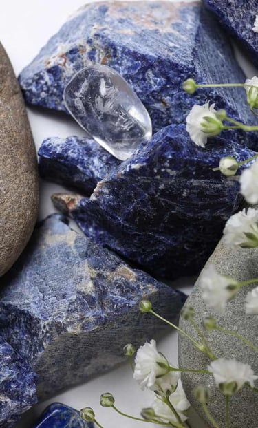 Piedras grises, azules y transparente con flores blancas encima.