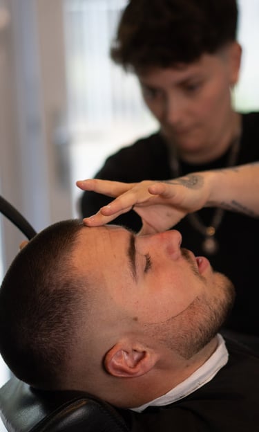 La barbière qui réalise une coupe à la lame dans les cheveux d'un homme