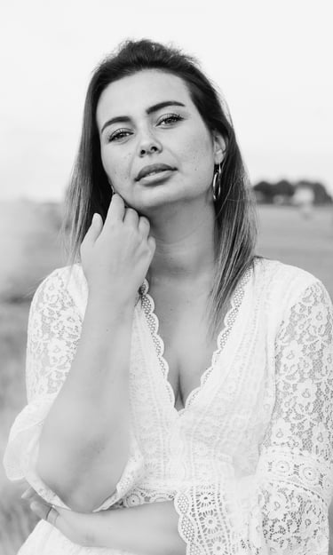 portrait féminin en noir et blanc se caressant la joue et regardant l'objectif en extérieur