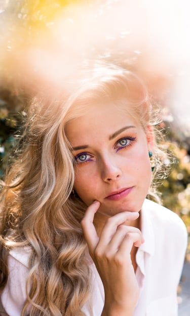 portrait femme blonde aux yeux bleus portant une main sous le menton
