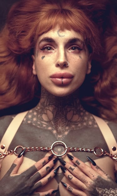 a woman with ginger hair with tattoos on her chest and wearing a harness
