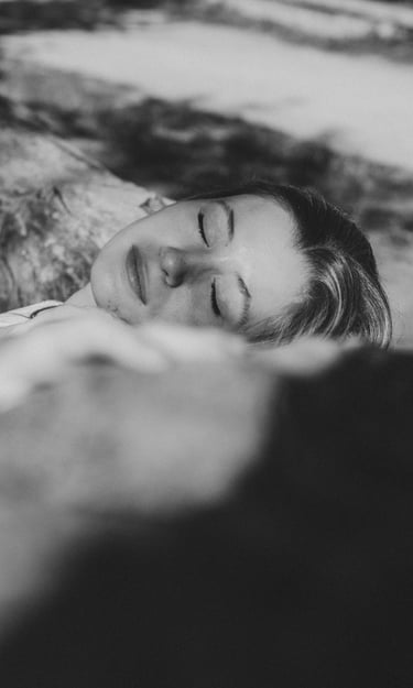 portrait féminin en noir et blanc yeux fermé allongé sur un tronc d'arbre 
