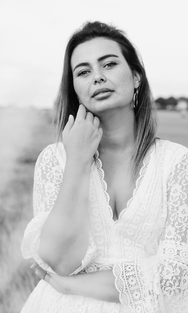 portrait féminin en noir et blanc se caressant la joue et regardant l'objectif en extérieur