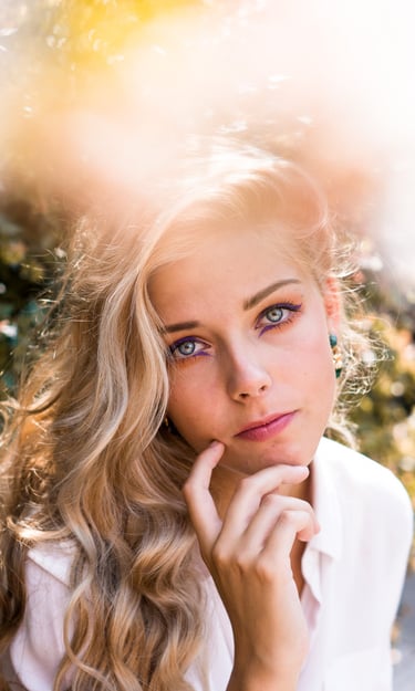 portrait femme blonde aux yeux bleus portant une main sous le menton