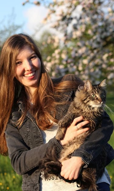 Una joven sonriente sostiene un gato atigrado de pelaje esponjoso