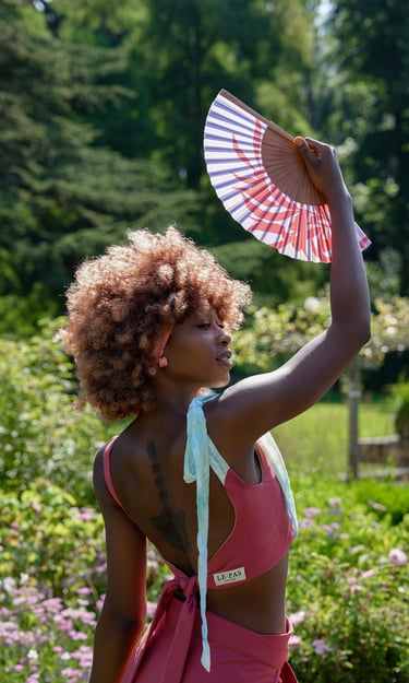 a woman model in a pink bikini suit holding a fan