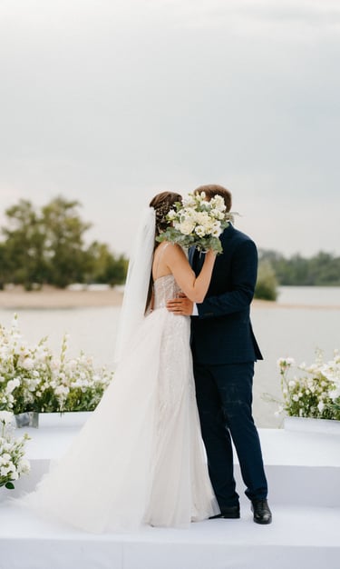 Bride and groom kiss at outdoor ceremony, bouquet raised—filmed by Imack Wedding Films, Glasgow.
