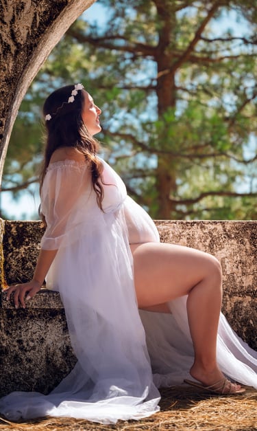 a woman in a white dress sitting on a stone wall
