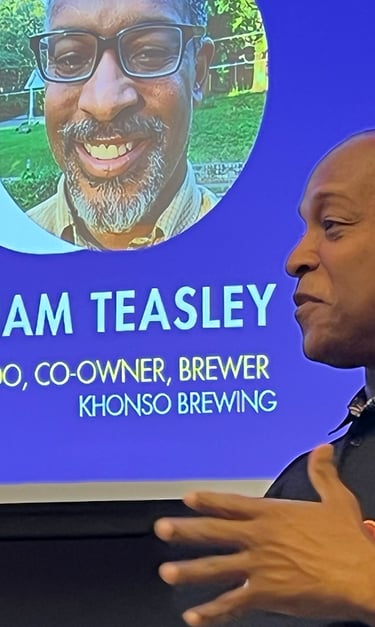 William Teasley of Khonso Brewing speaking at a business conference with his digital profile displayed behind him.