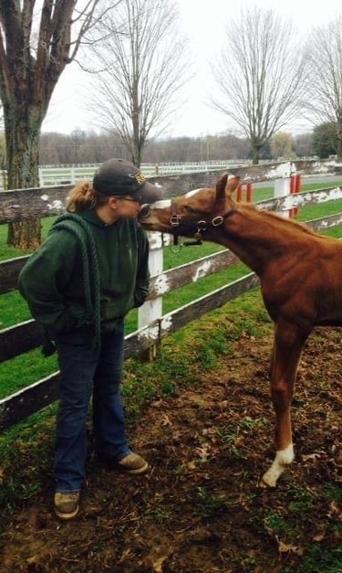 Erica Hayden kissing a horse in a field by a fence