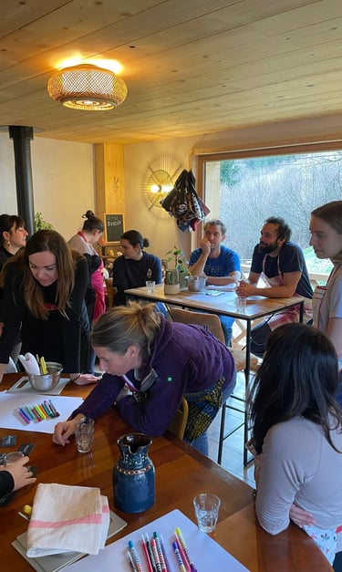 A group of people collaborating on creative projects at a wooden table in a brightly lit studio workshop.