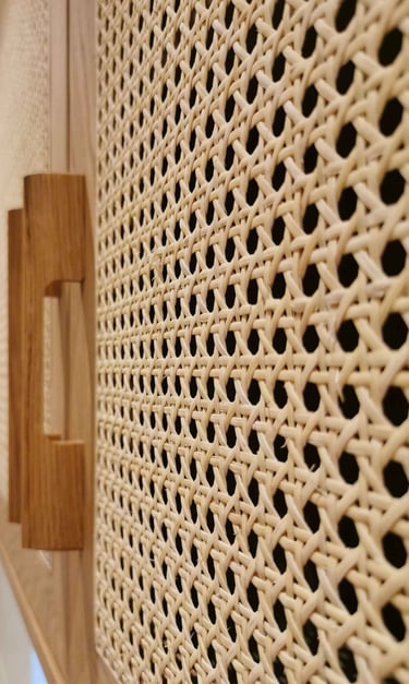 Close-up of a natural woven rattan cabinet door with a wooden handle in a modern boho interior.