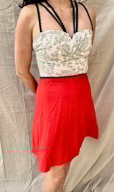 A strappy sundress with a green/white bodice and bright red skirt