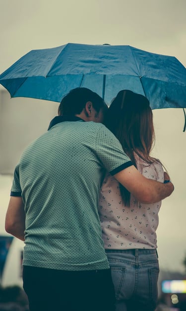 a husband and wife standing under an umbrella