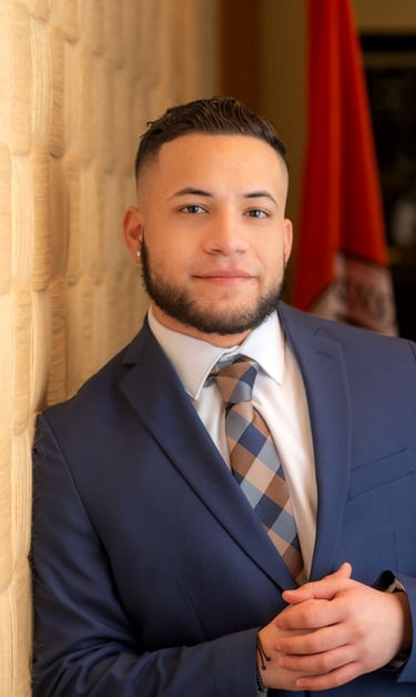 Isaac Vasquez in a blue suit with a white undershirt and blue and brown tie.