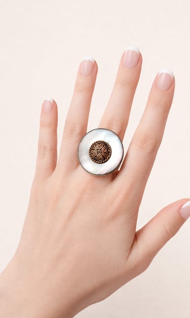 Vintage statement ring with large white mother of pearl and ornate bronze center on a hand.