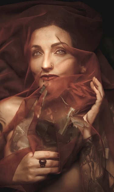 a woman with tattoo in a red dress with a veil on her head holding a red rose