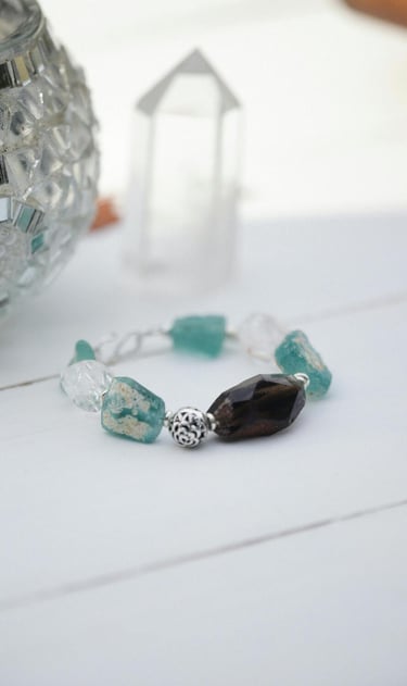 Pulsera de cuentas hecha a mano con cristal marino turquesa y cuarzo ahumado sobre una superficie blanca.