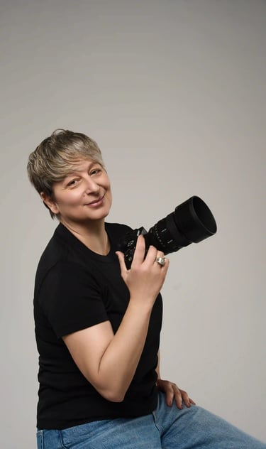 Tania Dina, fotógrafa profesional sosteniendo su cámara con una sonrisa auténtica