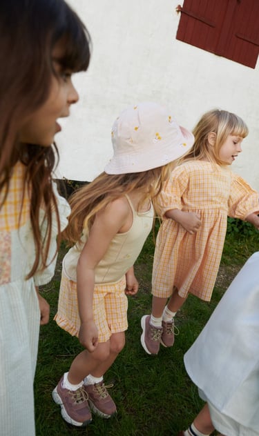 Photo from Wheat SS25 collection featuring 3 girls in orange checked dresses and outfits