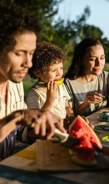 a family sitting at a table with a child eating nutritious foods