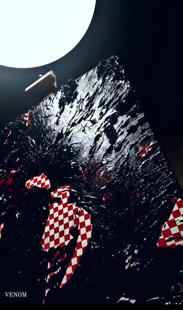 Textured black abstract oil painting with red and white checkered patterns under a studio light.