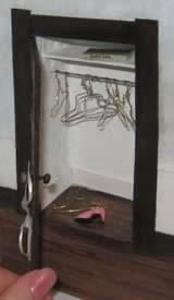 An altered book with a closet carved into it. Wire hangers and shoes inside the closet. 