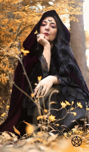 a mystical woman with a crescent tattooed on her forehead wearing a black dress and a black cape sit