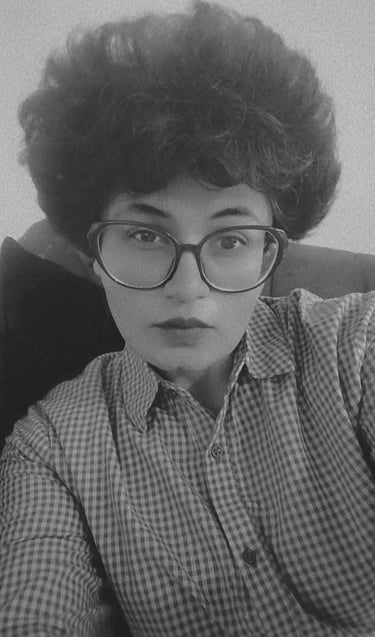 Eeta Noire, with a curly hair and glasses