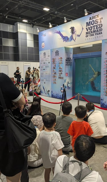 an audience watching an underwater performnce in a dive tank showing mermaids